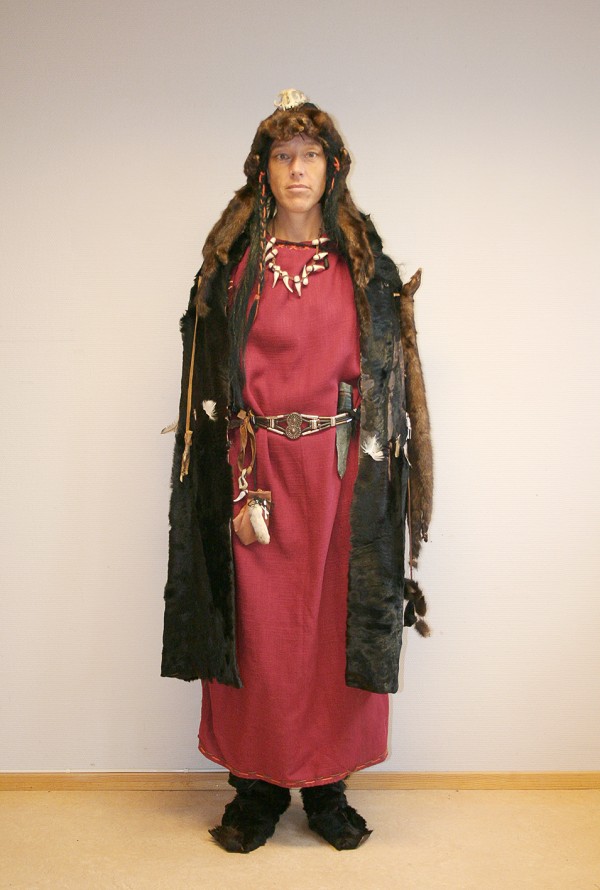 Volven i en lang rød bronsealderskjole, pelskappe og hodeplagg