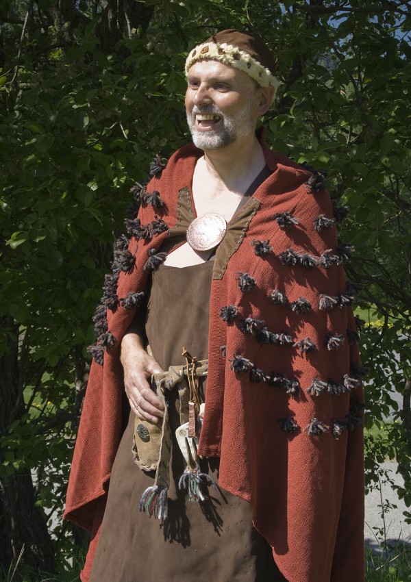 A man in a Bronze Age costume with a red furry cape and hat