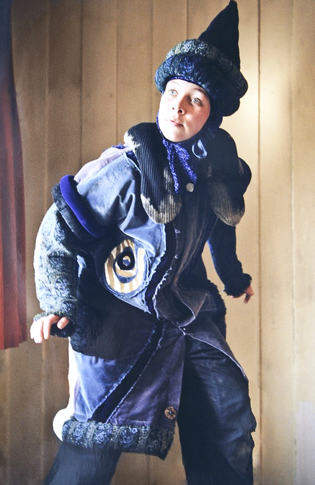 En skuespillerinne iført kostymet inkludert en blå spiss hatt og en blå, dekorert kåpe