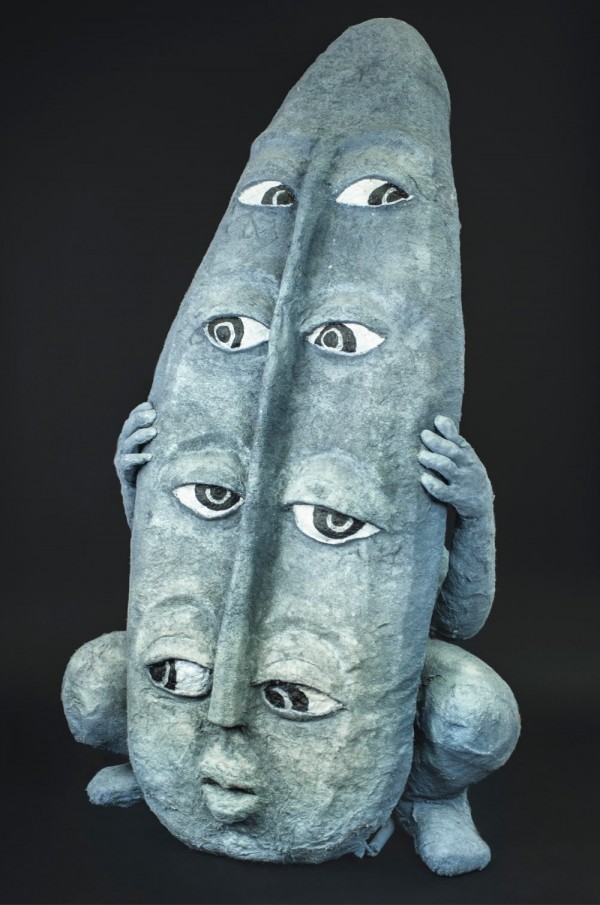 En face, a grey female figure hiding behind a grey shield with four pairs of eyes
