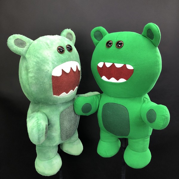2 green puppets standing against black background