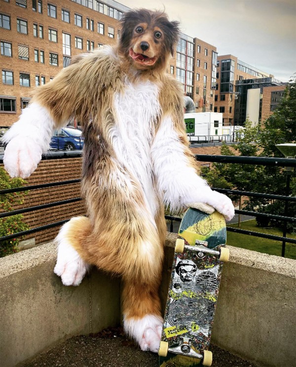 Man wearing a dog costume and holding a skateboard on a roof terrasse